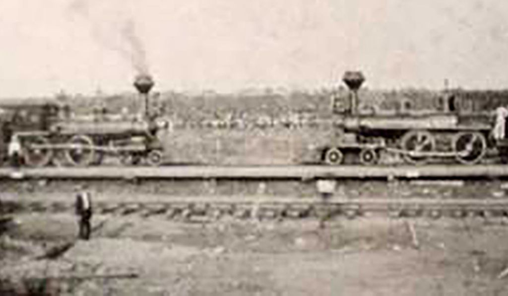 Two trains headed for a head-on collision, with a man standing in front