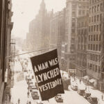 A flag flying outside a building. The flag says "A man was lynched yesterday"